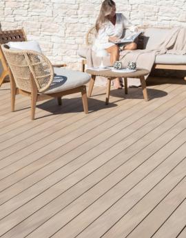Jeune femme lit dans un canapé posé sur une terrasse nuances chêne clair.