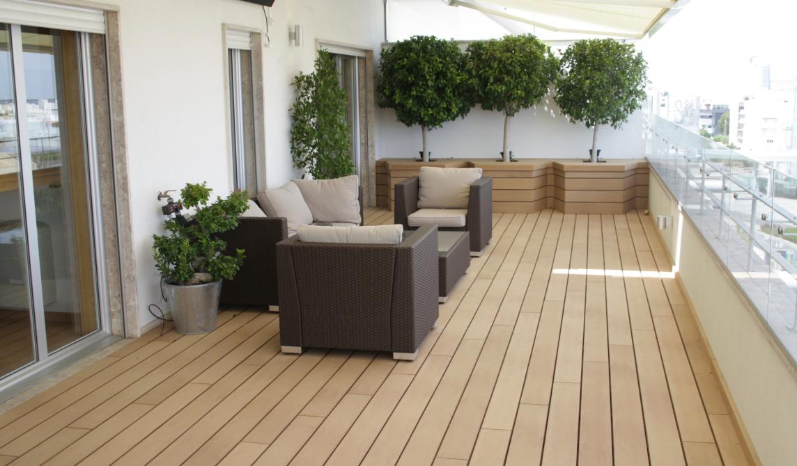 grand balcon en bois composite marron clair avec salon de jardin et jardinières, vue sur la ville