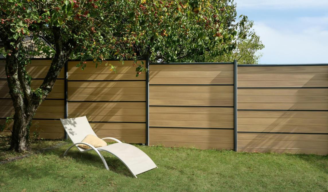 Clôture avec la nouvelle lame coloris nuances chêne clair de Silvadec, bain de soleil en premier plan