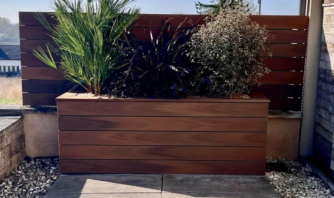 Jardinière moderne en bois composite Silvadec avec végétation mixte et arbustes décoratifs, idéale pour l'aménagement extérieur contemporain et durable