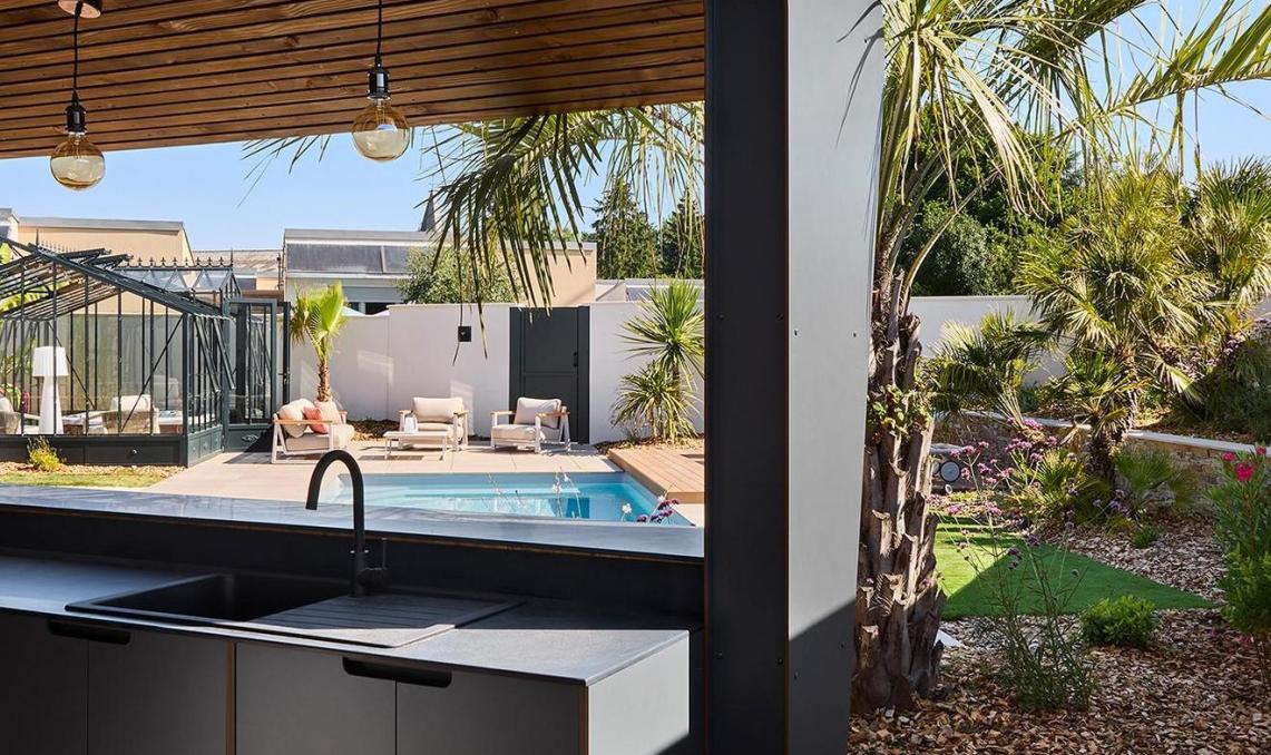 Angle extérieur du pool-house avec lames Nuances Ipé Silvadec au sol, cuisine d'extérieur et végétation méditerranéenne