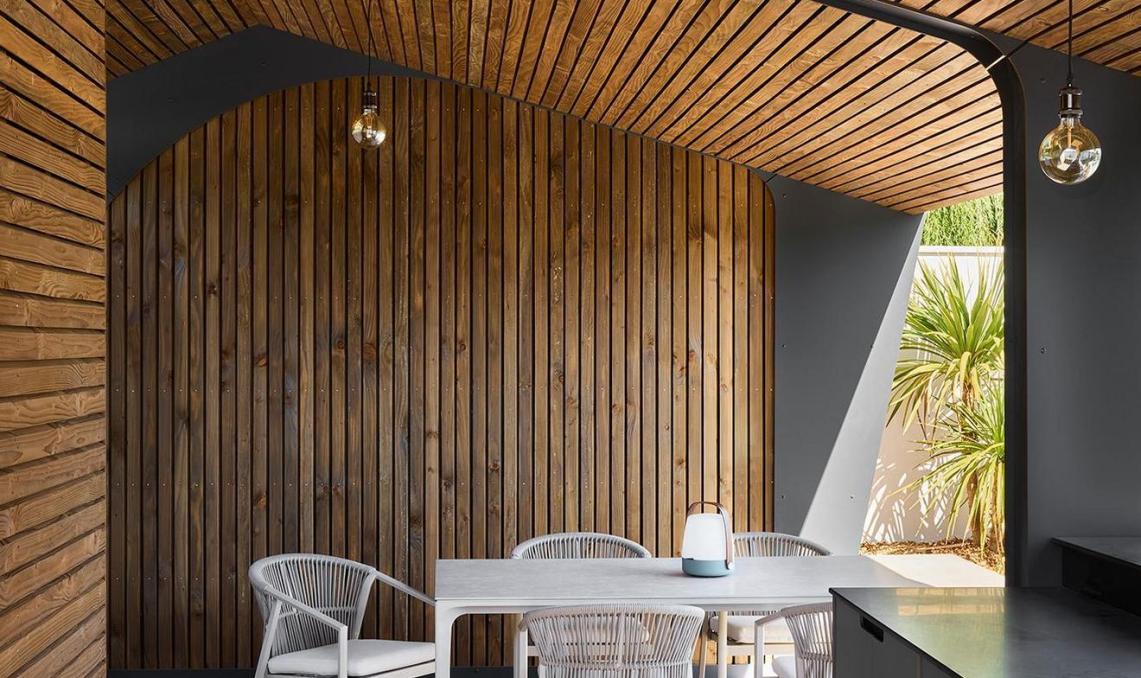 Intérieur pool-house : plancher composite Nuances Ipé, plafond voûté en lames bois, espace repas couvert