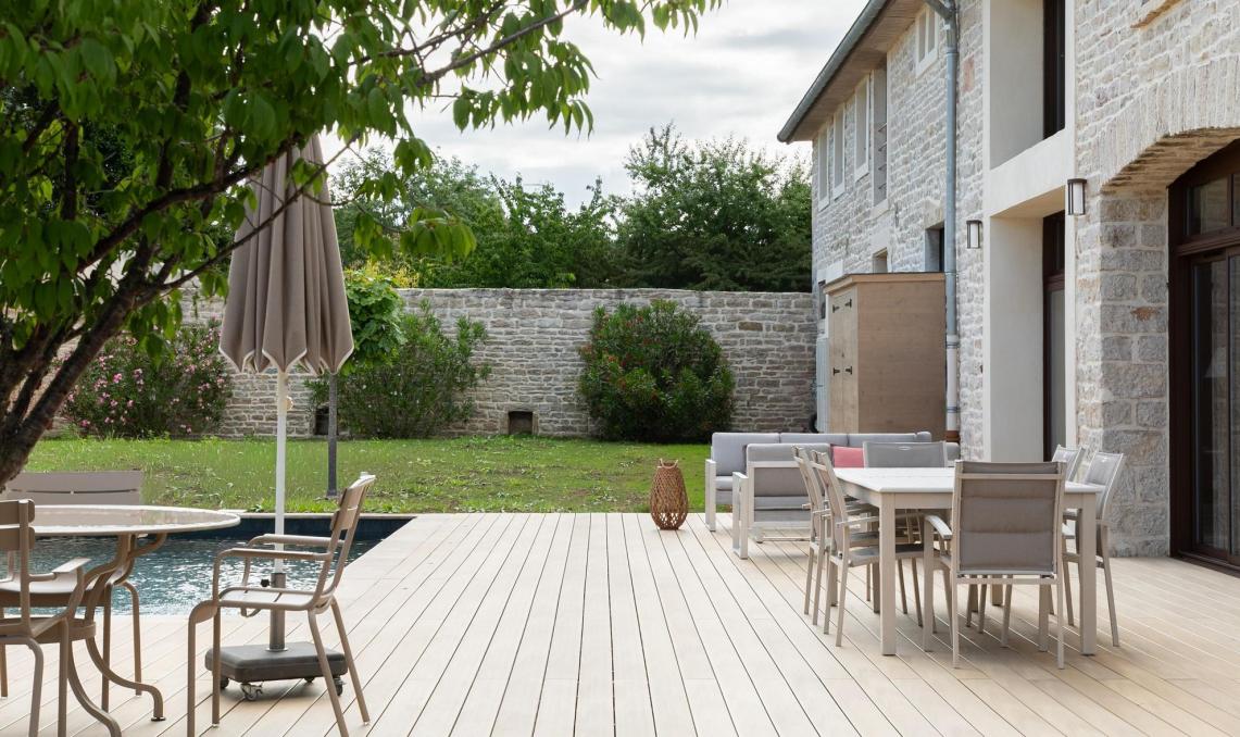 Salon extérieur installé sur la terrasse composite Nuances Chêne clair face à la piscine