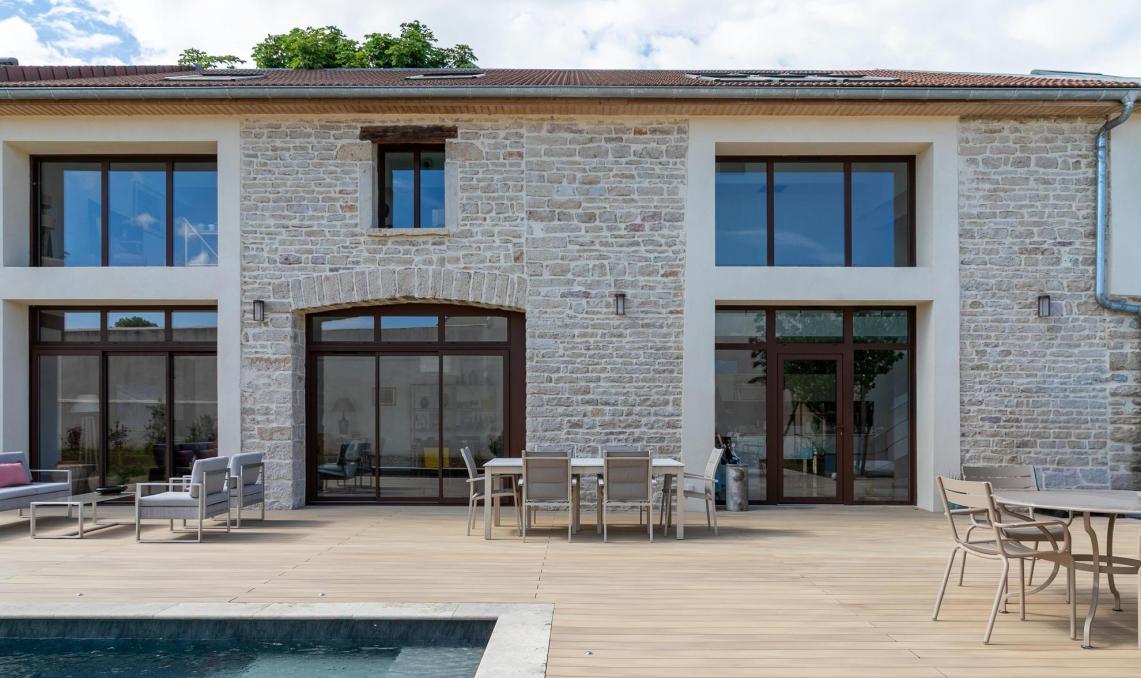 Terrasse composite Nuances Chêne clair autour d'une piscine, devant une ancienne cave en pierre rénovée à Beaune
